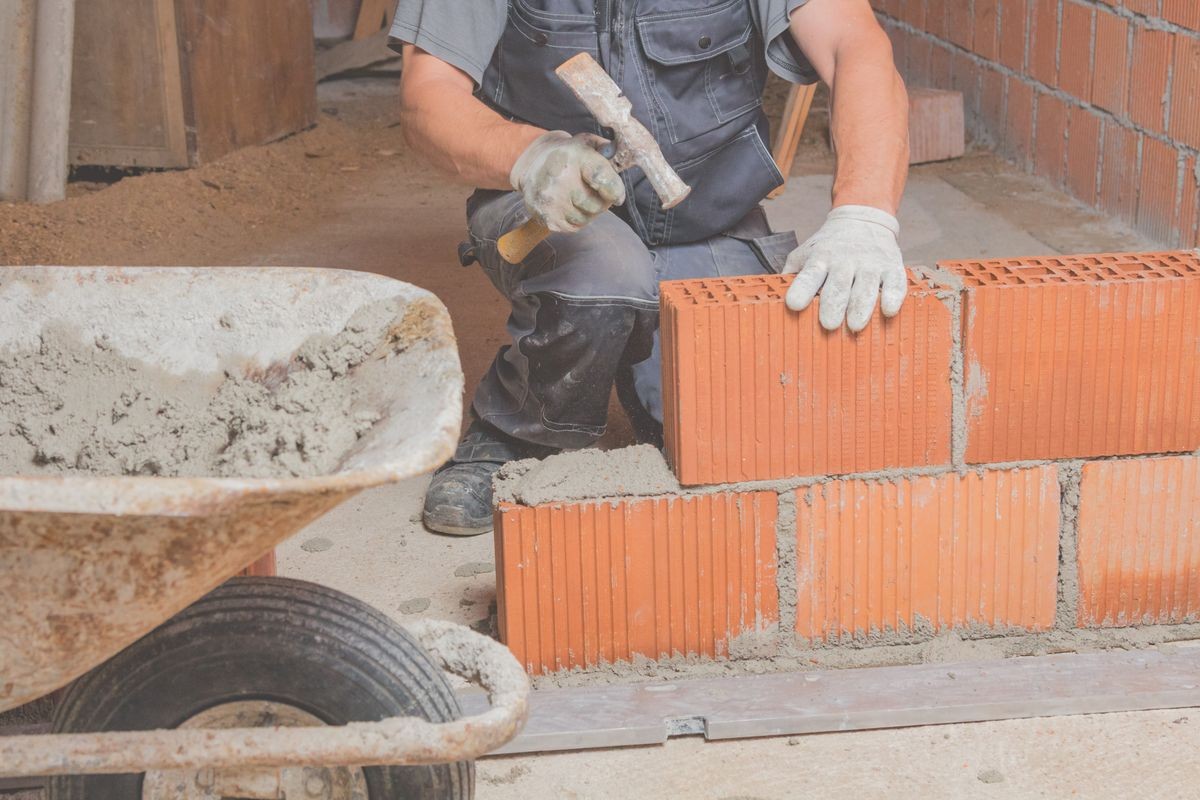 Real construction worker bricklaying the wall indoors.